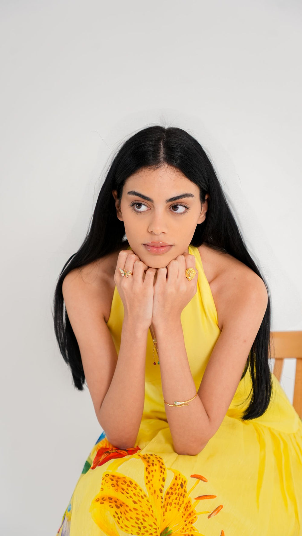 Model resting her chin on her hands wearing the Butterfly Ring and Lion Ring in 18K gold